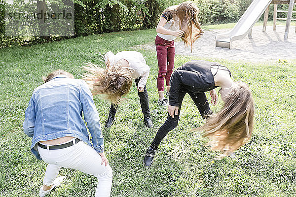 Vier Mädchen schütteln ihre Köpfe mit Löwenzahnsamen bedeckt