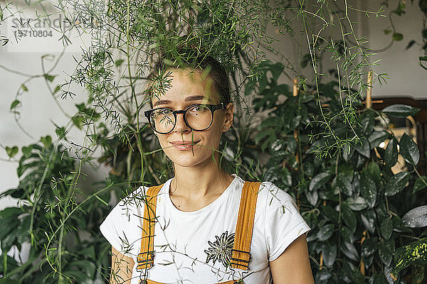 Porträt einer jungen Frau umgeben von Pflanzen