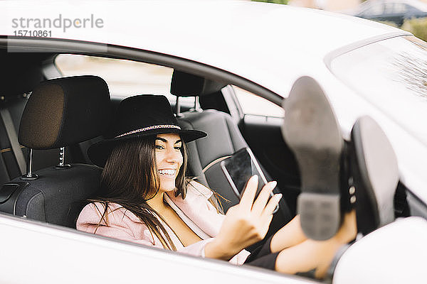 Geschäftsfrau  die ein Smartphone benutzt und einen Selfie im Auto mitnimmt
