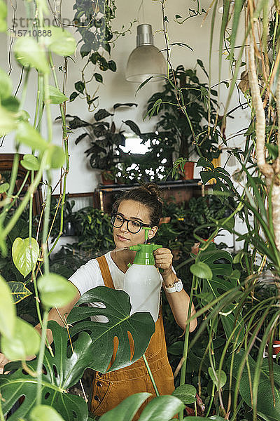 Junge Frau  die in einem kleinen Laden Pflanzen pflegt
