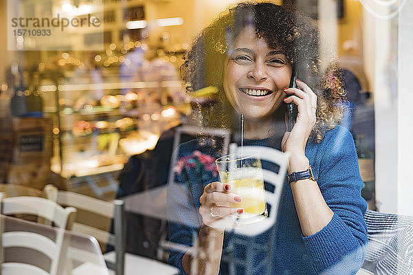 Porträt einer glücklichen Frau am Telefon in einem Cafe