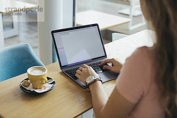 Studentin tippt im Café an ihrem Computer