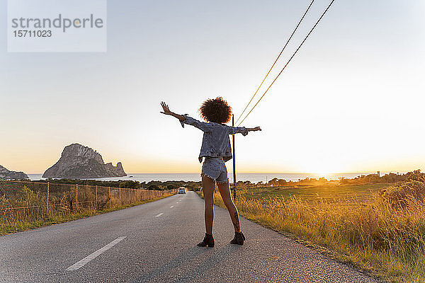 Junge Frau steht bei Sonnenuntergang auf der Straße  Ibiza