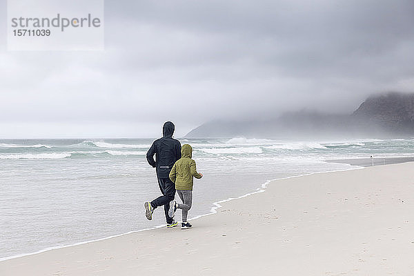 Rückansicht von Vater und Tochter beim Joggen am Strand  Nordhoek  Westkap  Südafrika