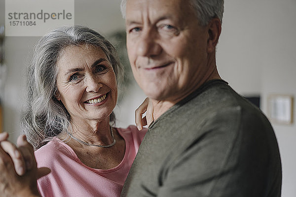Porträt eines glücklichen Seniorenpaares  das zu Hause tanzt
