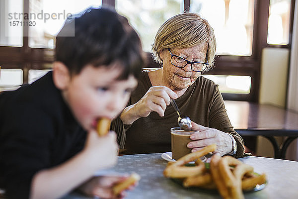 Großmutter und Enkel frühstücken gemeinsam zu Hause am Tisch