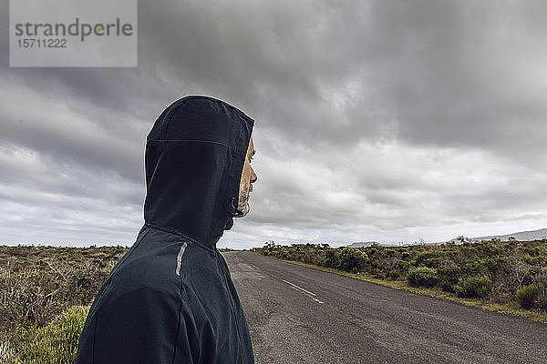 Mann in ländlicher Szene mit Kapuzenjacke und Blick in die Ferne  Cape Point  Westkap  Südafrika