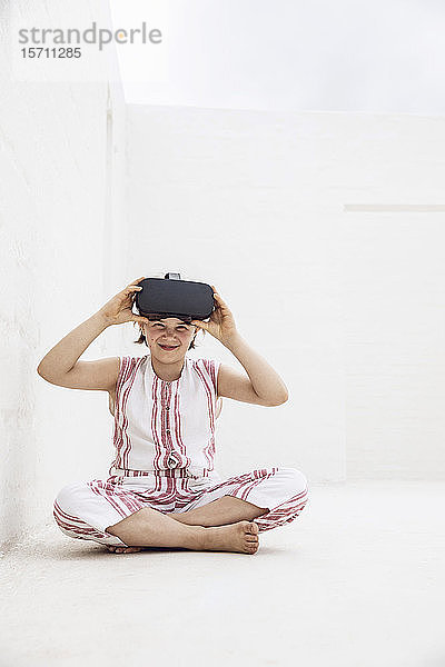 Mädchen mit VR-Brille sitzt auf dem Boden des leeren Raumes