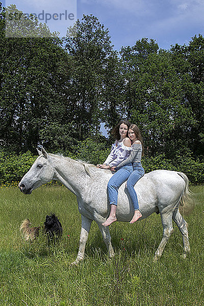 Porträt von zwei besten Freunden beim gemeinsamen Reiten auf einem Pferd