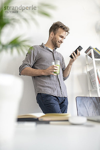 Lächelnder Mann benutzt Smartphone im Büro