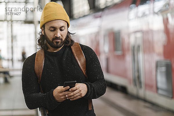 Junger Mann mit Smartphone am Bahnsteig  Berlin  Deutschland