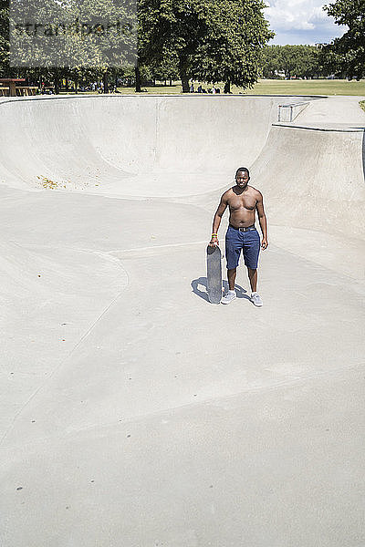 Mann mit Skateboard im Skatepark