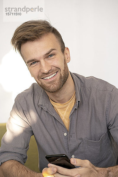 Porträt eines lächelnden Mannes mit einem Smartphone