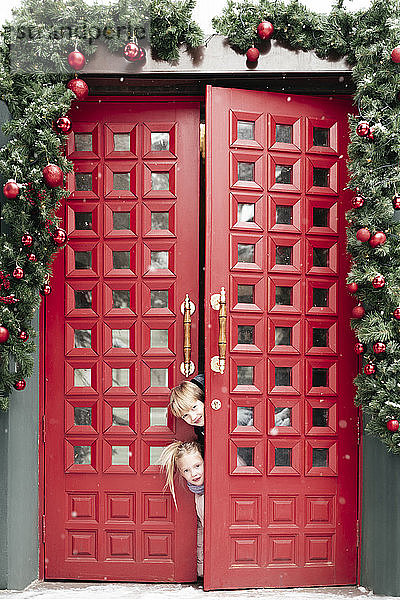 Porträt von Geschwistern an der Tür zur Weihnachtszeit