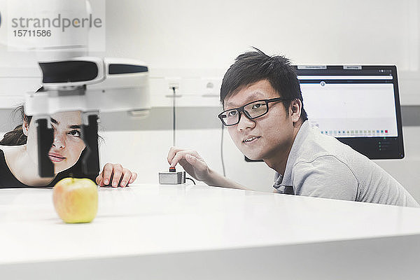 Studenten  die an einem Universitätsinstitut Robotik studieren und mit einem Apfel experimentieren