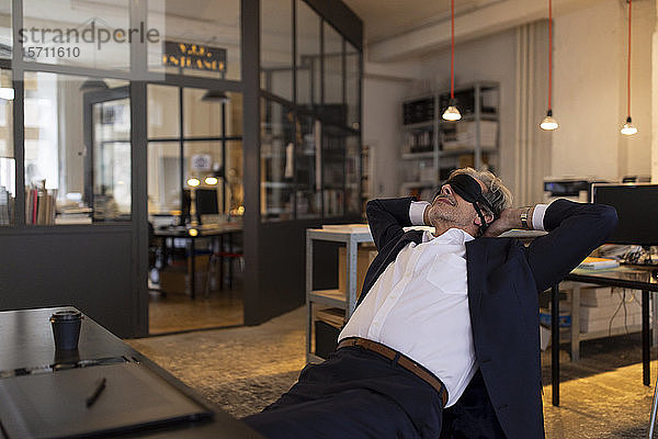 Leitender Geschäftsmann mit einem Power-Nap am Schreibtisch im Büro