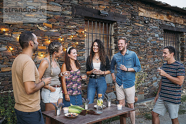 Eine Gruppe von Freunden unterhält sich und trinkt im Freien in einem Steinhaus