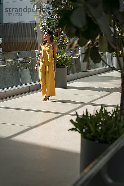 Modisch gekleidete Frau in Gelb auf dem Skywalk