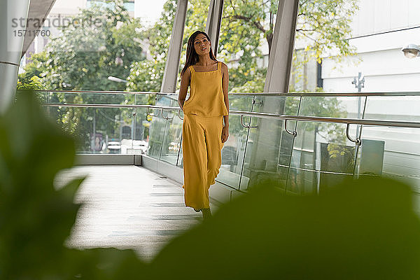 Porträt einer modisch gekleideten Frau in Gelb beim Spaziergang auf der Terrasse