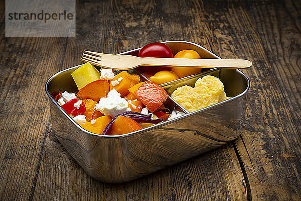 Metall-Lunchbox mit Salat aus im Ofen gebackenem Gemüse und herzförmiger Polenta