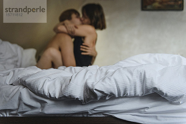 Umarmen und Küssen von Paaren auf dem Bett