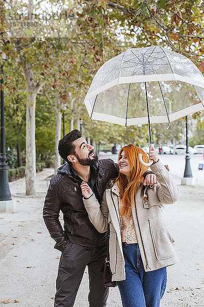 Verliebtes Paar beim Herbstspaziergang mit durchsichtigem Regenschirm