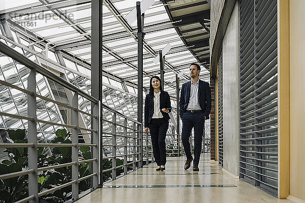 Geschäftsmann und Geschäftsfrau gehen in modernem Bürogebäude
