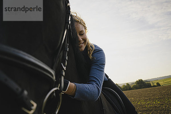 Liebevolle Frau zu Pferd auf einem Feld auf dem Land