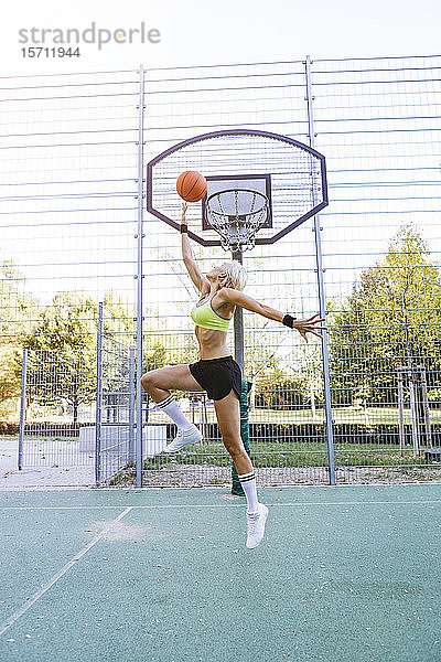 Blonde Frau spielt Basketball  taucht ein