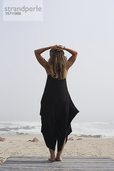 Rückansicht einer am Meer stehenden Frau  Kreuz am Kap  Namibia