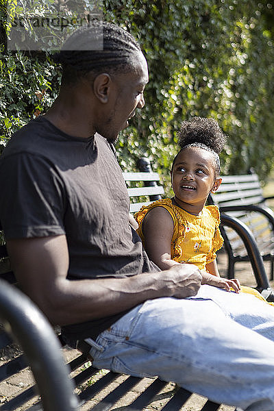 Vater und Tochter sitzen auf einer Bank in einem Park