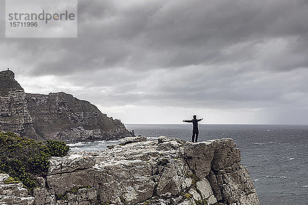 Mann steht auf felsiger Klippe und schaut zum Horizont  Cape Point  Westkap  Südafrika