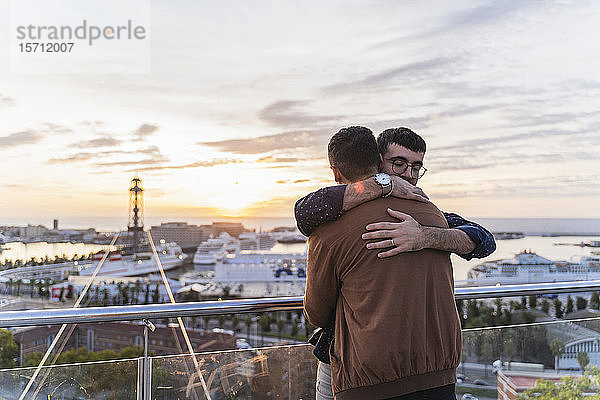 Schwules Paar umarmt sich auf einem Aussichtspunkt über der Stadt mit Blick auf den Hafen  Barcelona  Spanien