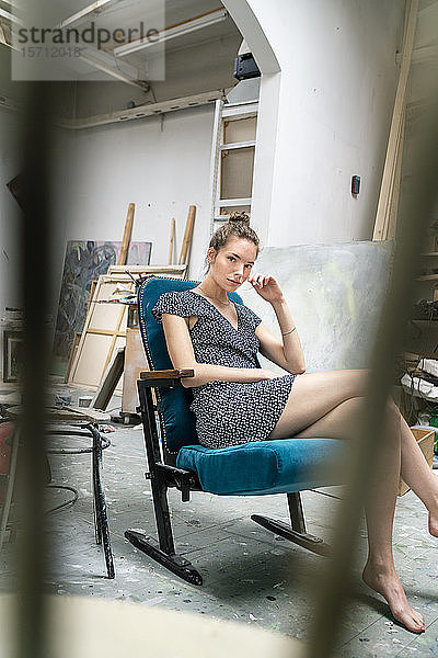 Junge Künstlerin sitzt in ihrem Atelier