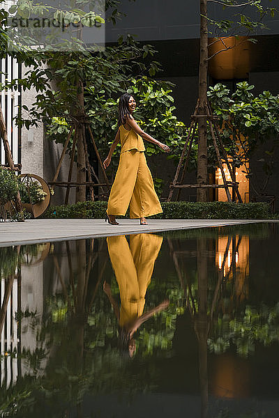 Modische Frau in gelb gekleidet tanzt in der Stadt