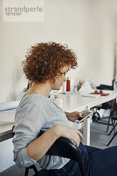 Geschäftsfrau  die mit einem Smartphone eine Pause im Büro macht