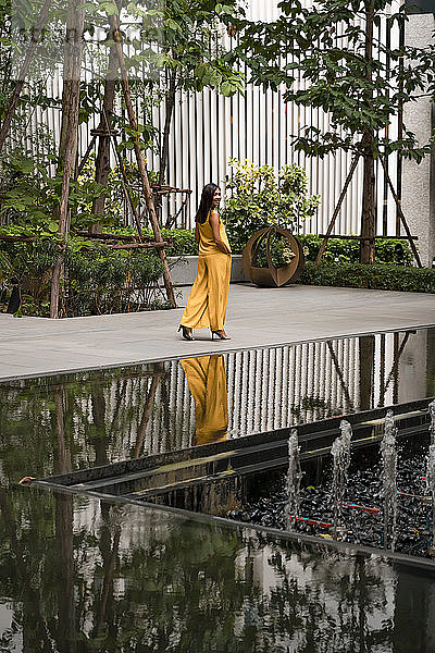 Modisch gekleidete Frau in Gelb spaziert durch die Stadt