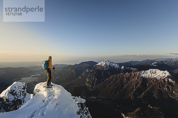 Bergsteiger steht auf einem verschneiten Berg und geniesst die Aussicht  Lecco  Italien