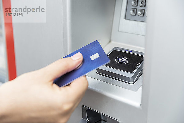 Nahaufnahme einer Hand  die eine Kreditkarte hält und kontaktlos bezahlt