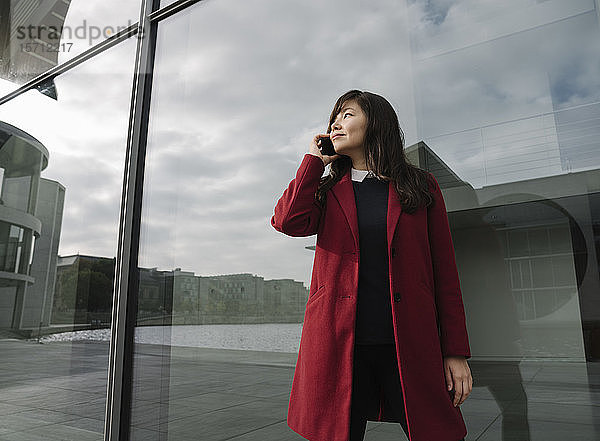 Geschäftsfrau  die in der Nähe eines modernen Gebäudes steht und ein Smartphone benutzt