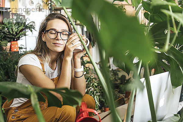 Junge Frau bei einer Kaffeepause in einem kleinen Gartenbaubetrieb