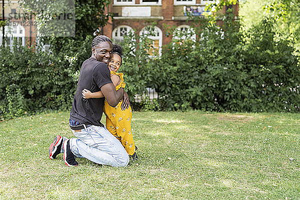 Glücklicher Vater umarmt Tochter in einem Park