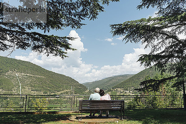 Rückenansicht eines älteren Ehepaares  das auf einer Bank sitzt und auf die Aussicht schaut  Jaca  Spanien