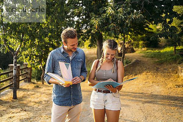 Mann und Frau auf einer Exkursion mit Mappen in ländlicher Landschaft
