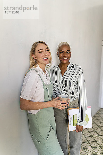 Porträt von zwei lächelnden Frauen mit Papier und Tasse Kaffee