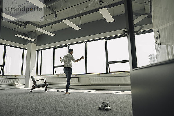 Reifer Geschäftsmann praktiziert Yoga in leerem Büro