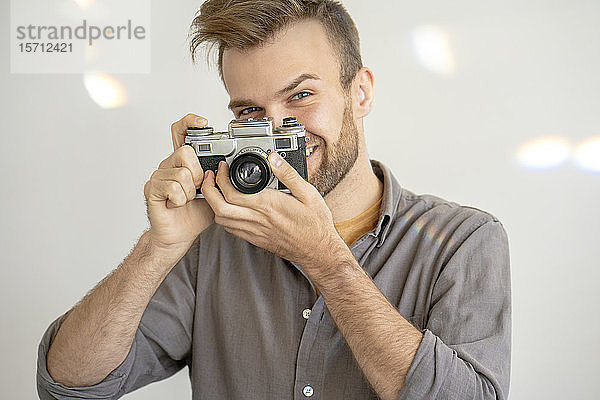 Porträt eines lächelnden Mannes  der mit einer altmodischen Kamera fotografiert