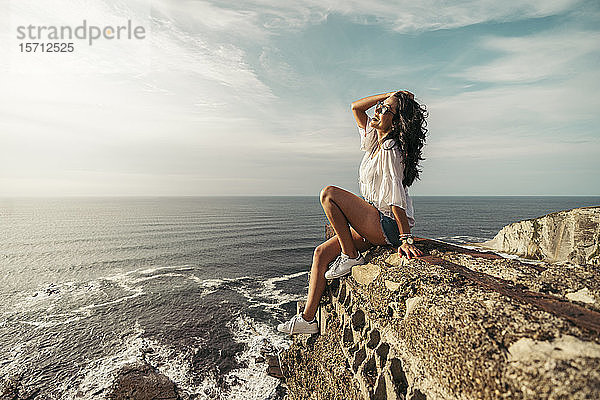 Junge Frau sitzt auf einem Aussichtspunkt mit der Hand im Haar  Getxo  Spanien