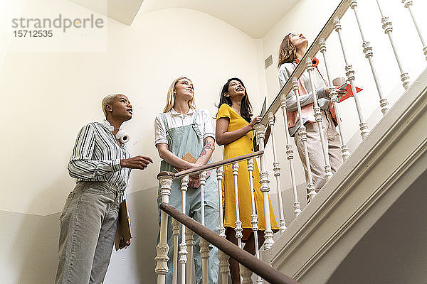 Vier selbstbewusste Frauen gehen im Treppenhaus die Treppe hinauf