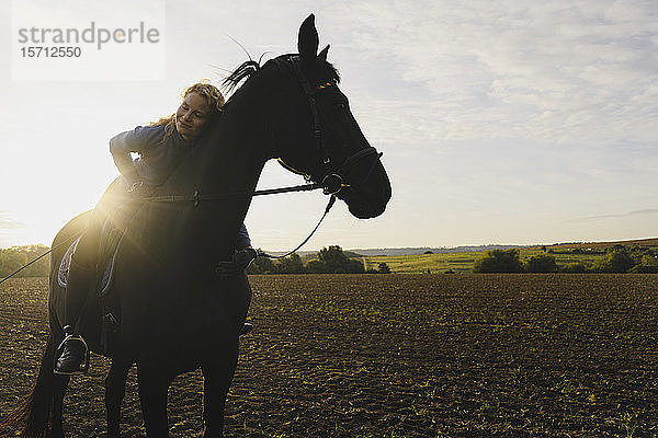 Liebevolle Frau zu Pferd auf einem Feld auf dem Land